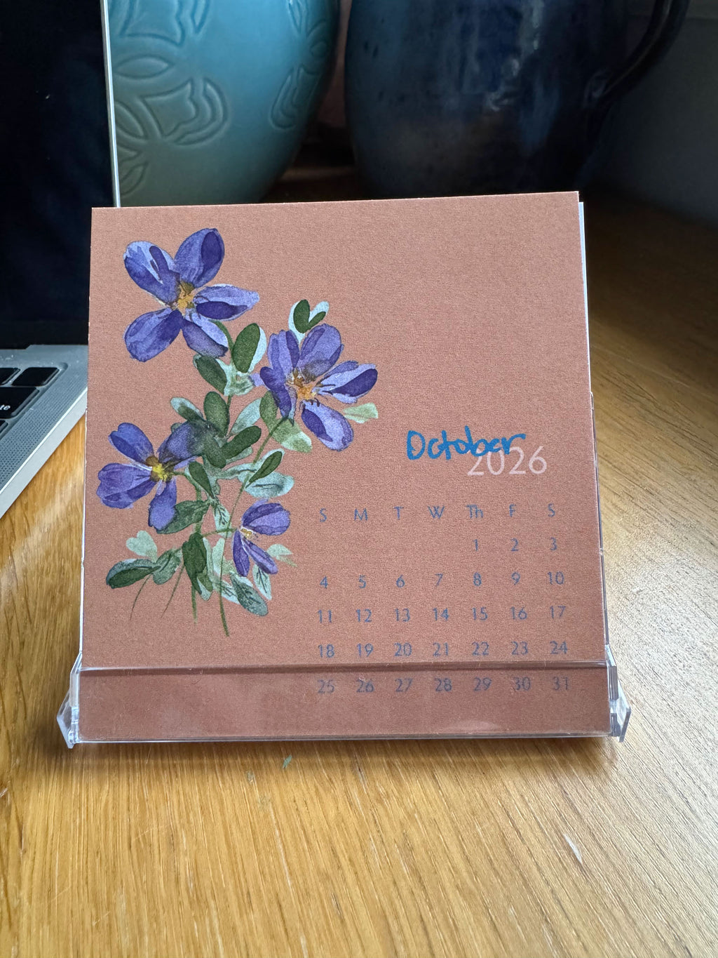 Calendar with floral design on a wooden surface October 2026