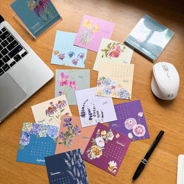 Colorful mini desk calendar on a desk with a laptop and mouse.