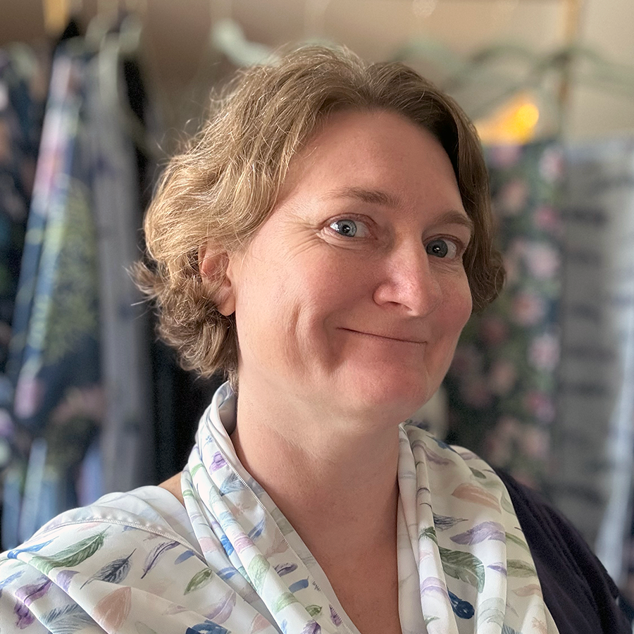The artist, Monica, wearing one of her scarfs with a colorful feather pattern. 