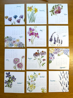 Calendar with floral designs for each month on a wooden surface