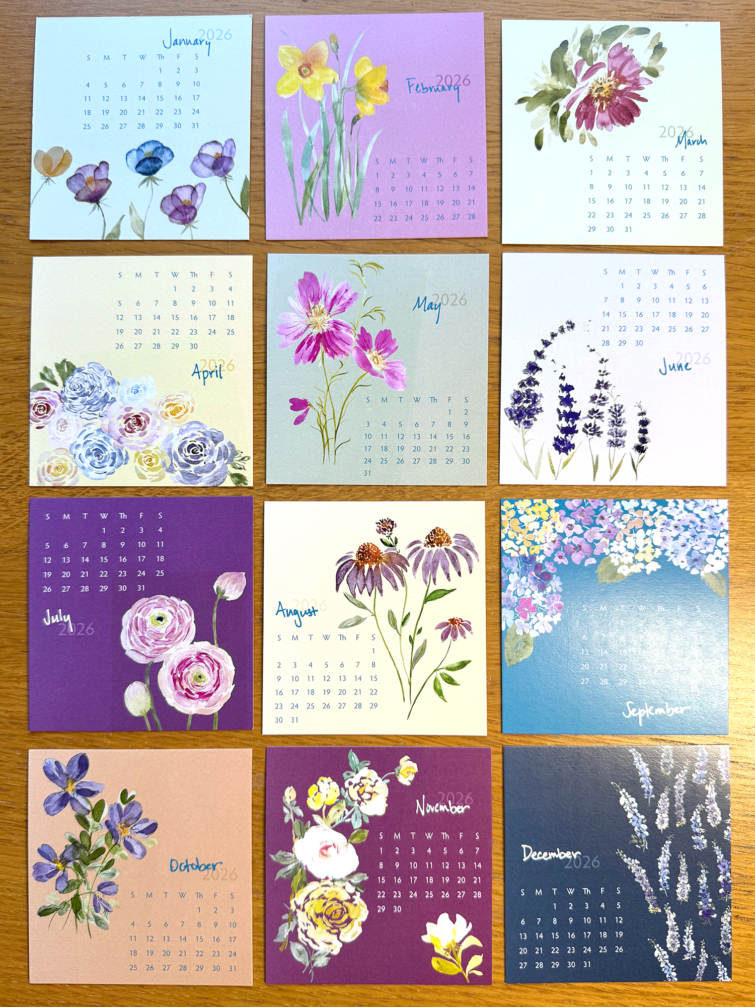 Calendar with floral designs for each month on a wooden surface