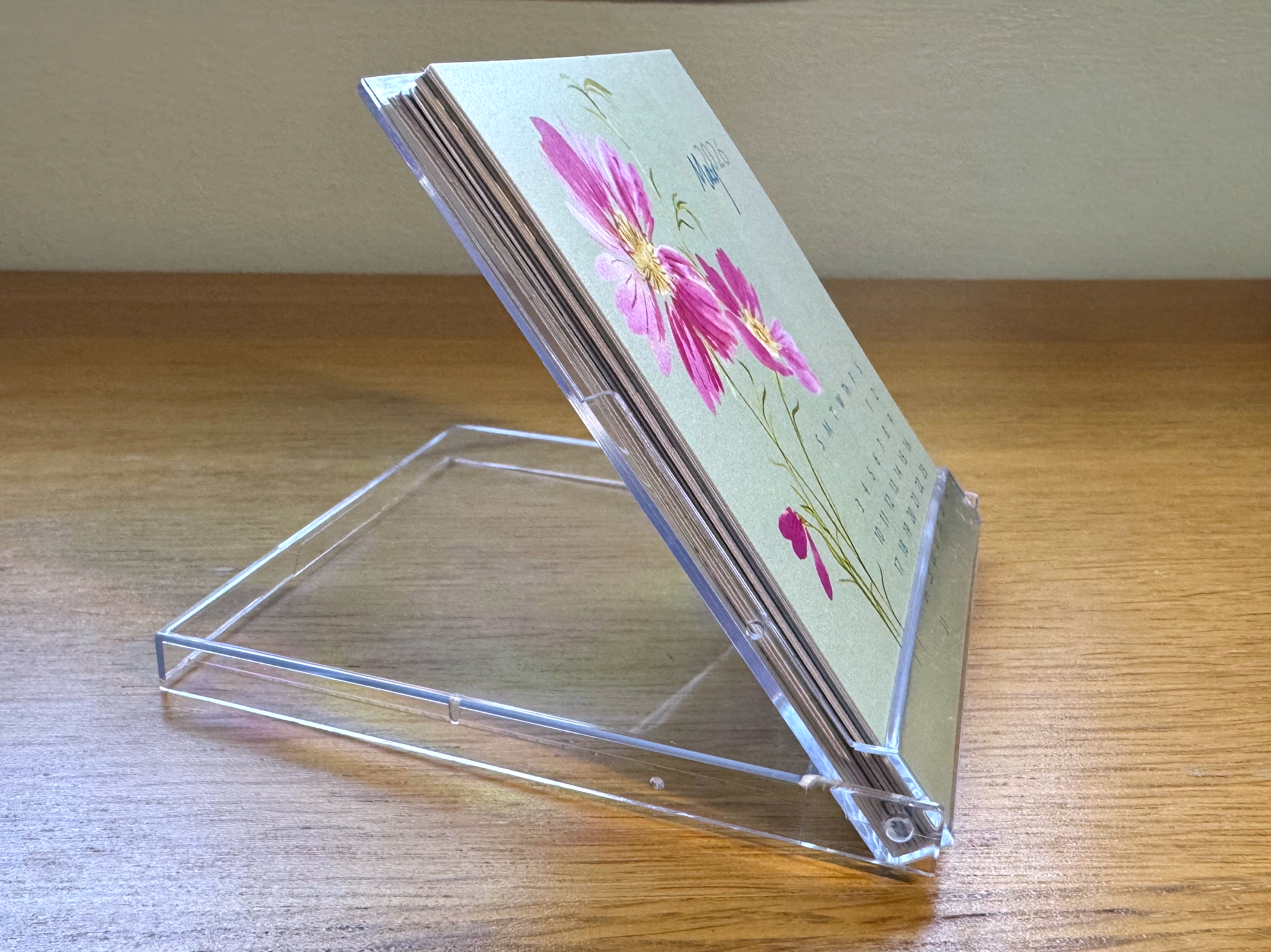 Clear acrylic card holder with floral design on a wooden surface