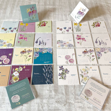 Collection of floral-themed calendars and cards on a textured surface