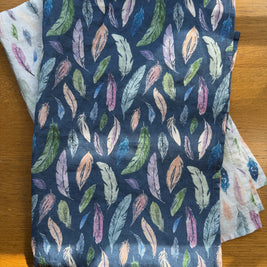 Two folded Tea Towels with feather pattern on a wooden surface